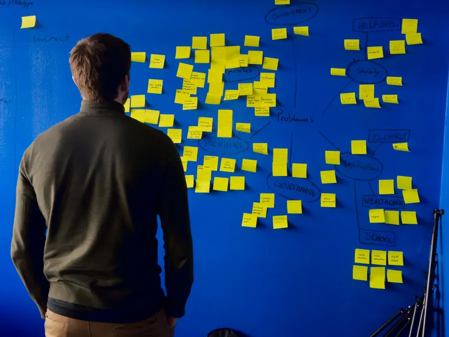 Profissional diante de um painel de post-its organizando as etapas de um lançamento